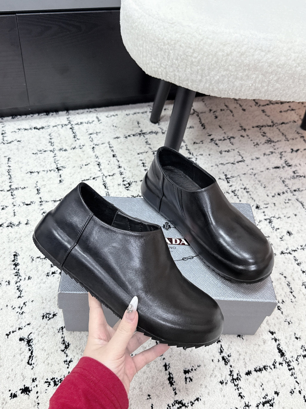 Black leather low-profile loafers with rounded toe, PRADA logo on insole; held