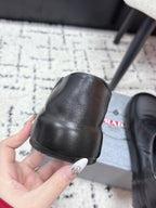 Black leather loafer with thick outsole and toe edge detail; held by hand