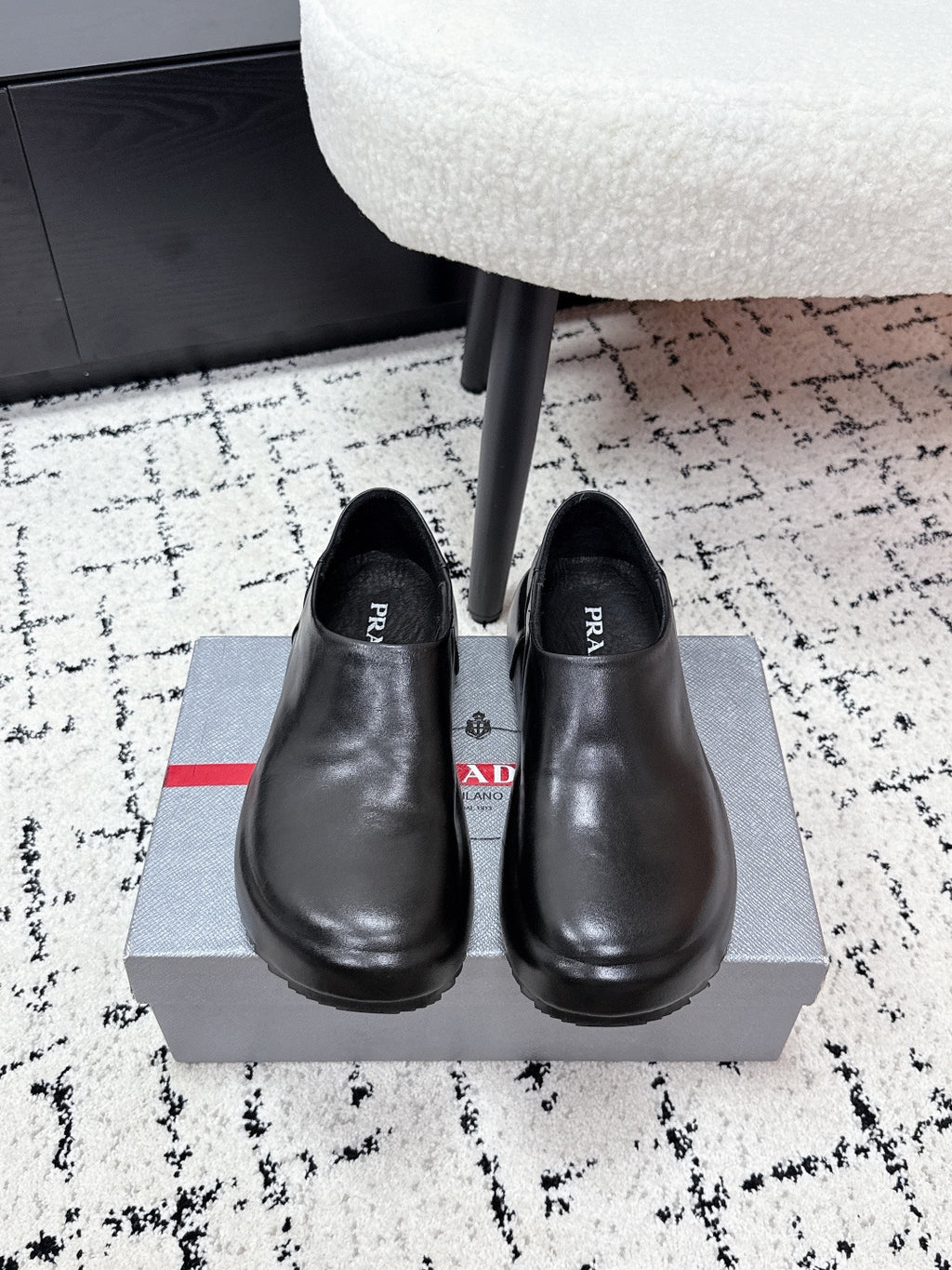 Black leather slip-on loafers with rounded toe and PRADA logo on insole
