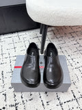 Black leather slip-on loafers with rounded toe and PRADA logo on insole