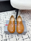 Brown leather slip-on loafers with rounded toe; Prada logo on insole.