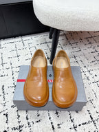 Brown leather slip-on loafers with rounded toe; Prada logo on insole.
