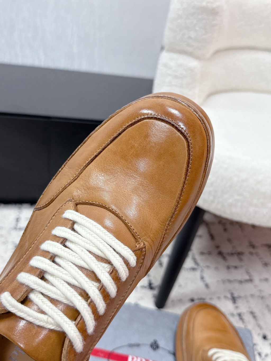 Tan leather Prada sneaker toe with white lace-up, close-up