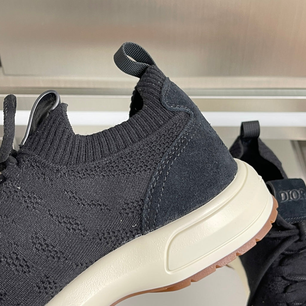 Close-up of black knit sneaker upper with cream midsole and brown outsole edge.