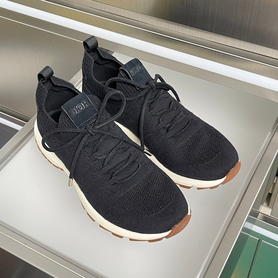 Black knit lace-up sneakers with thick white soles and brown rubber detail.