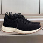Black knit sneaker with lace-up front and white sole, Dior logo on tongue.