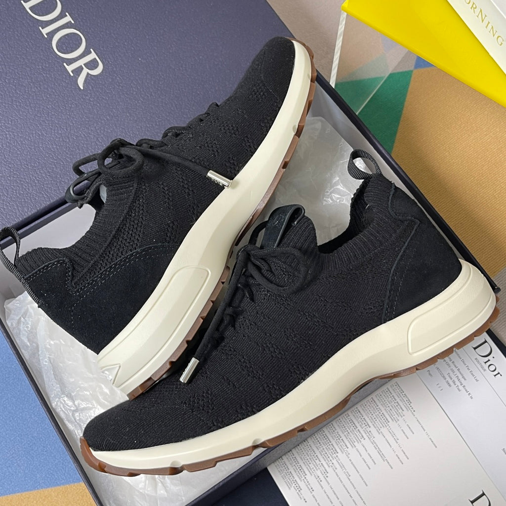 Black knit sneakers with lace-up closure and white rubber sole, Dior on side.