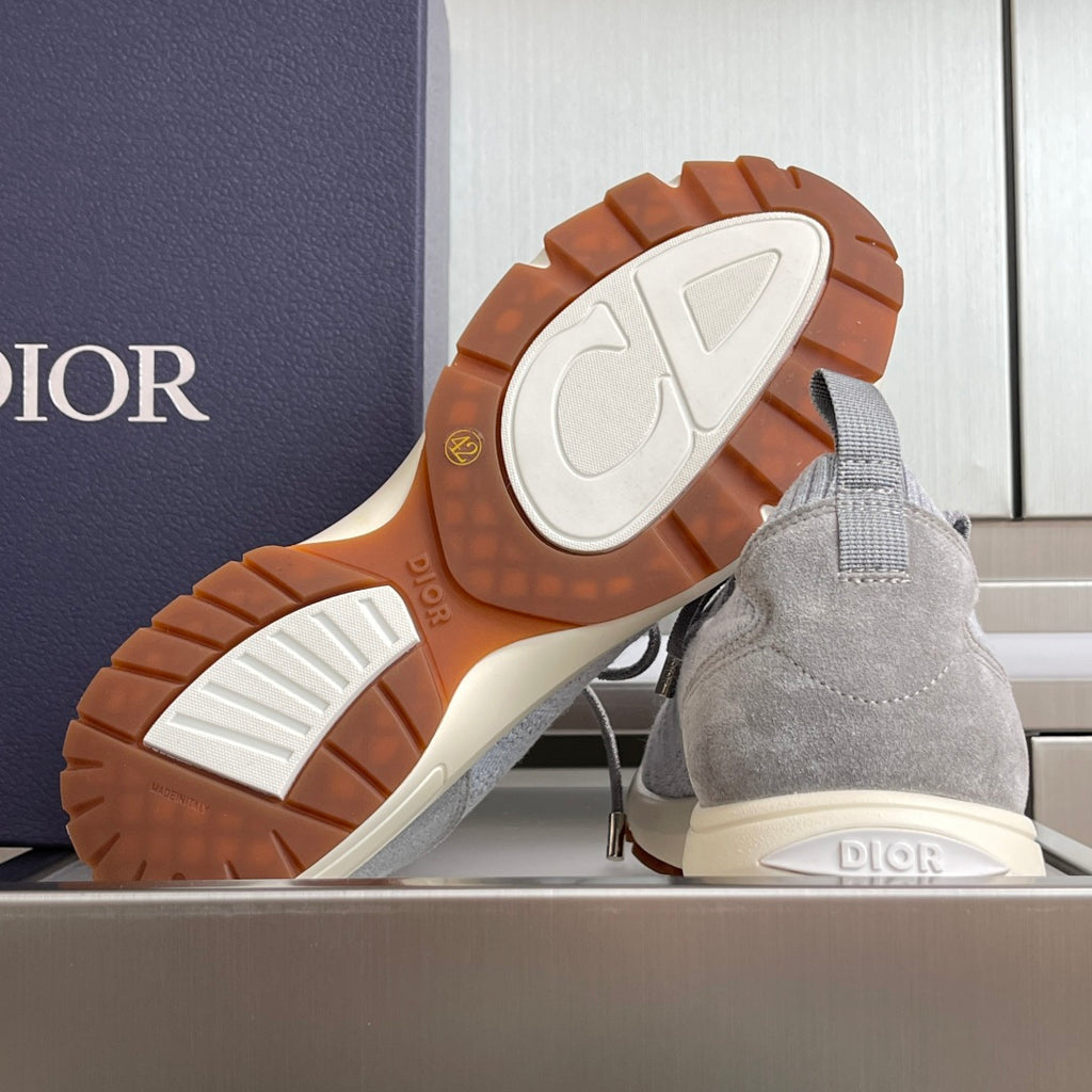 Light grey sneakers showing treaded rubber outsole and Dior logo on heel