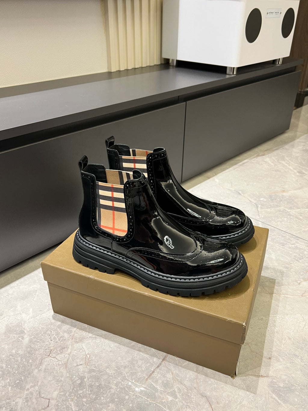 Burberry black patent Chelsea boots on a tan box with elastic side panels