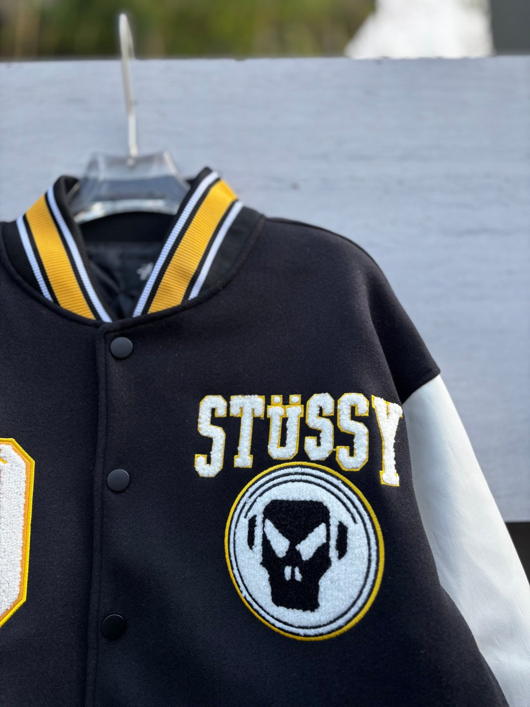 Varsity jacket with STUSSY text and round emblem on black chest panel