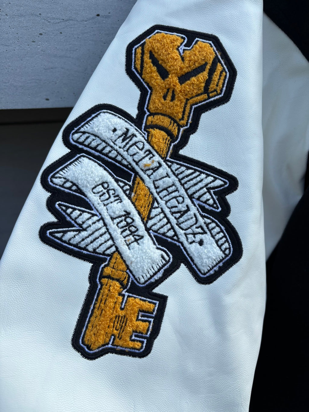 Varsity jacket sleeve patch on light fabric with yellow and white embroidered graphics