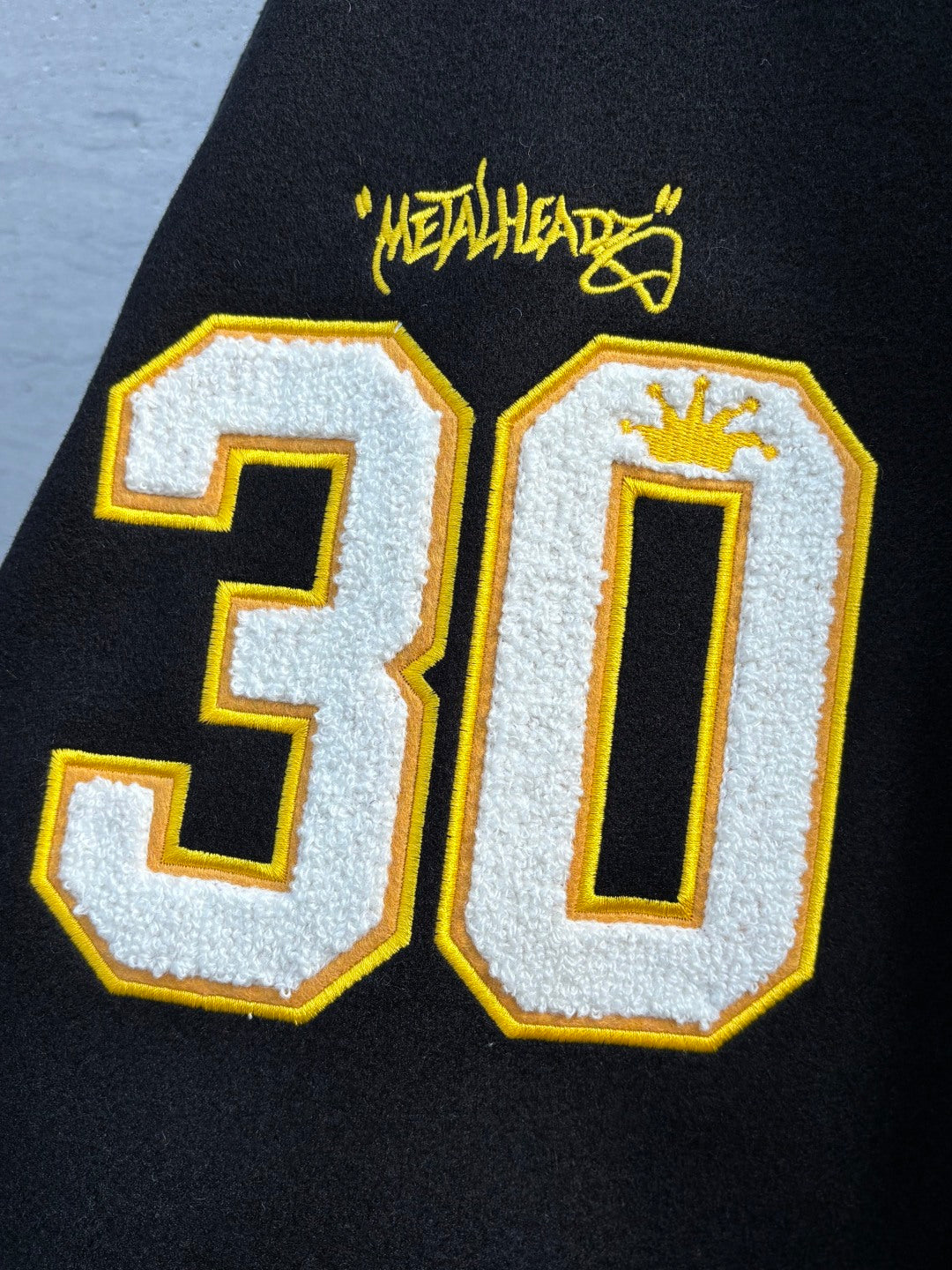 Varsity jacket with large stitched 30 numbers in yellow and white on black