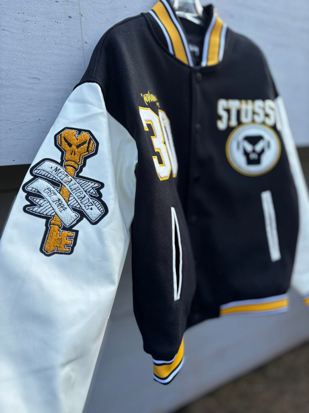 Varsity jacket with contrast sleeves, front Stussy logo patch, and sleeve emblem patches