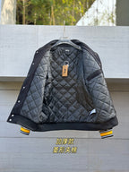 Quilted varsity jacket with dark gray body, black sleeves, snap front and hanging tag