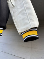 Varsity jacket cuff close-up with dark ribbing and yellow-and-white striped band
