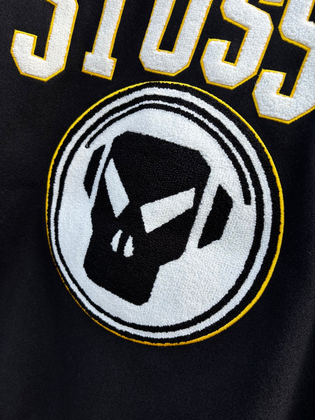Black Stussy sweatshirt with circular logo and black-and-white face graphic