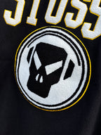 Black Stussy sweatshirt with circular logo and black-and-white face graphic