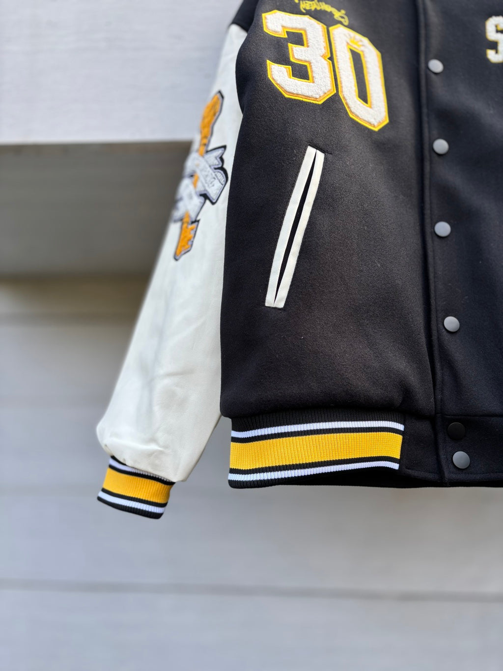 Varsity jacket sleeve with large 30 patch, striped rib cuff, black and white panels
