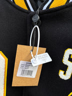 Varsity jacket neckline close-up with snap placket and hanging brand tags