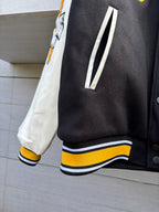 Varsity jacket ribbed hem and cuffs with yellow-and-white striped trim on dark body