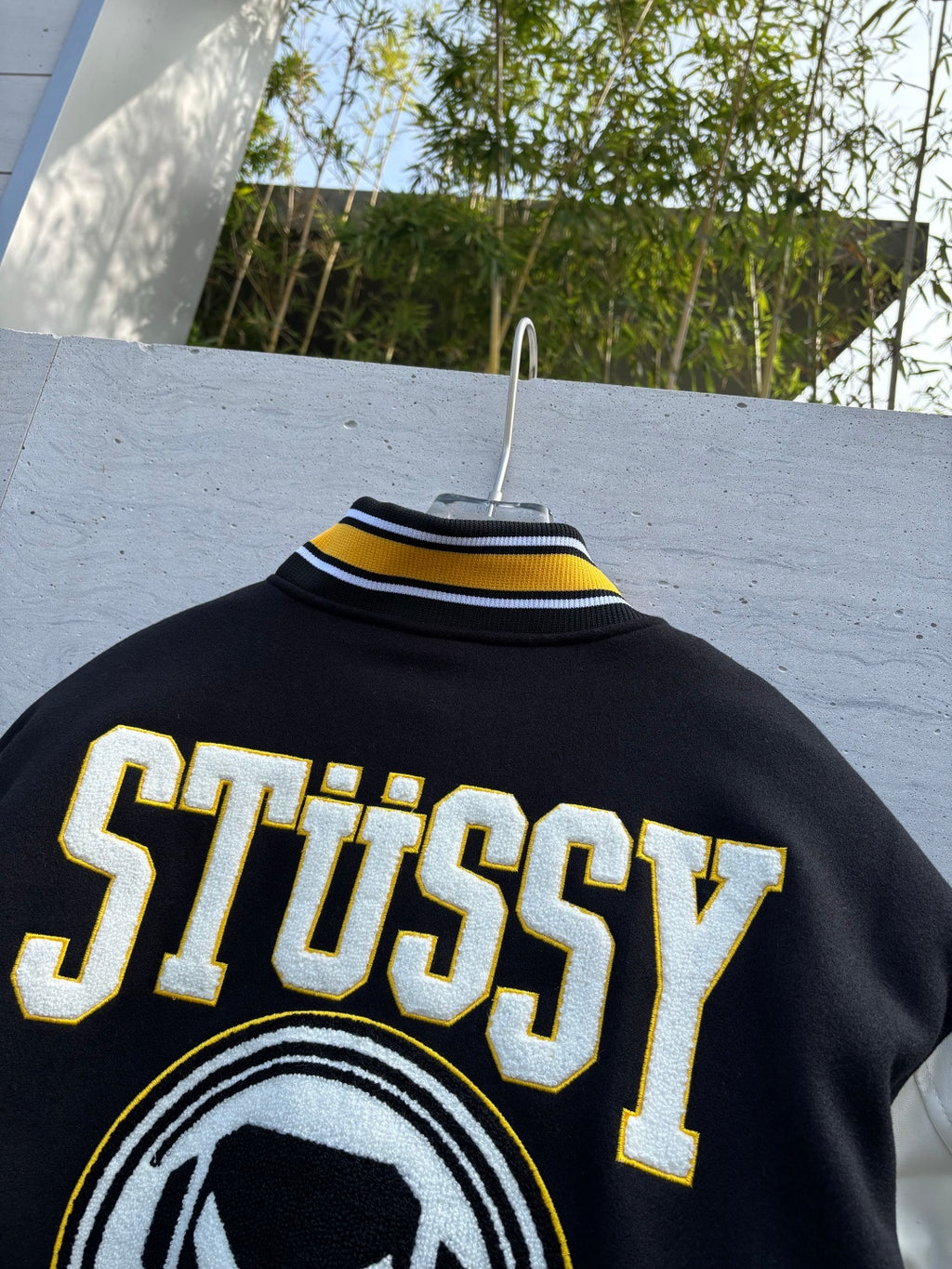 Black varsity jacket back with large Stussy lettering and ribbed collar