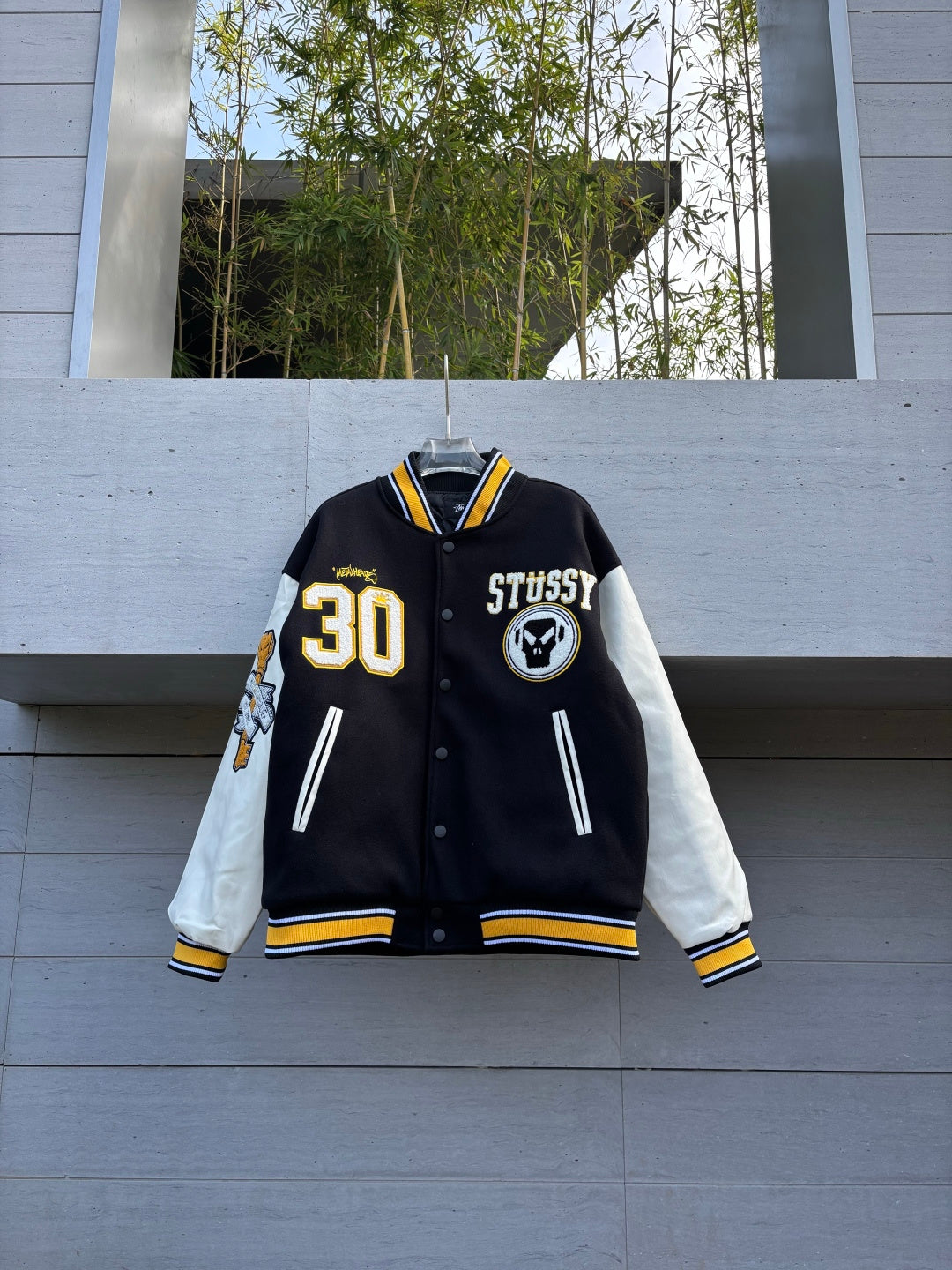 Varsity jacket with black body, white sleeves, yellow striped cuffs, snap button front