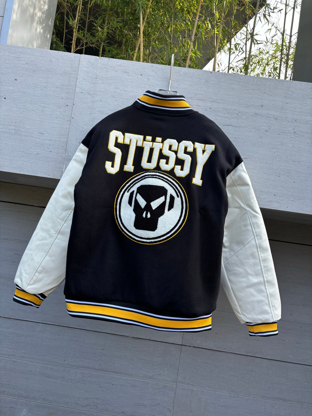 Black and white varsity jacket with Stussy logo patch on back