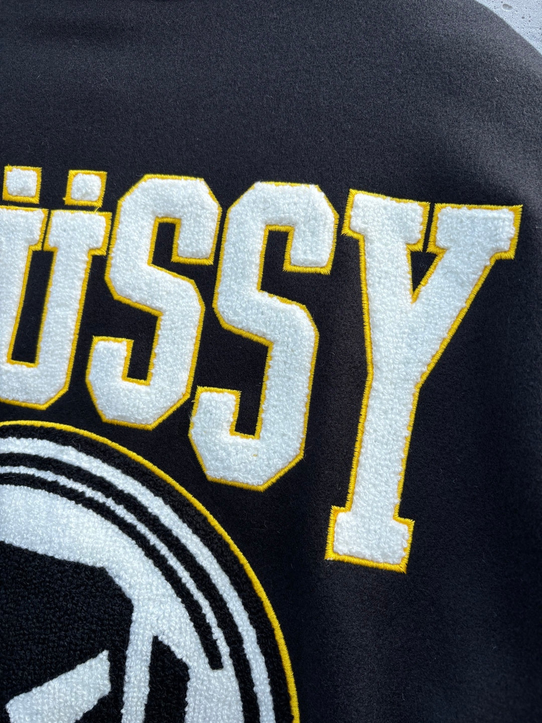 Black sweatshirt with large STUSSY lettering and partial circular logo print