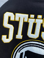 Black sweatshirt with STUSSY lettering and partial circular logo print