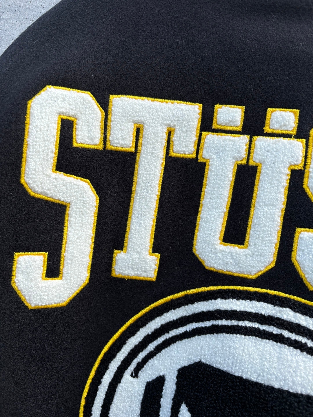 Black sweatshirt with STUSSY lettering and partial circular logo print
