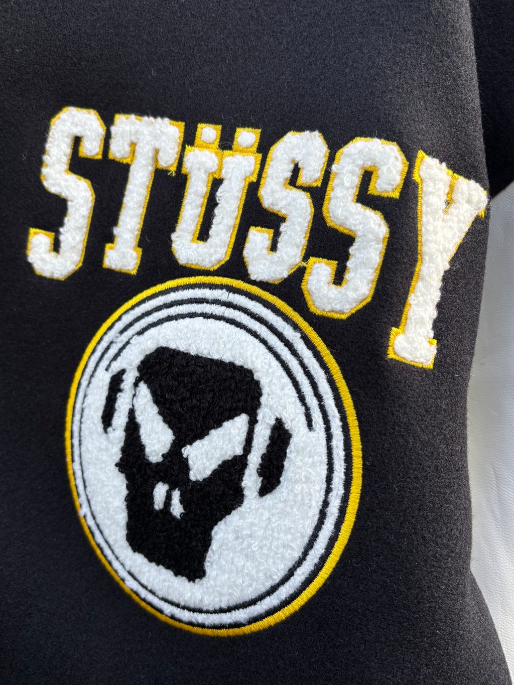 Black varsity jacket embroidered Stussy logo patch and bear emblem