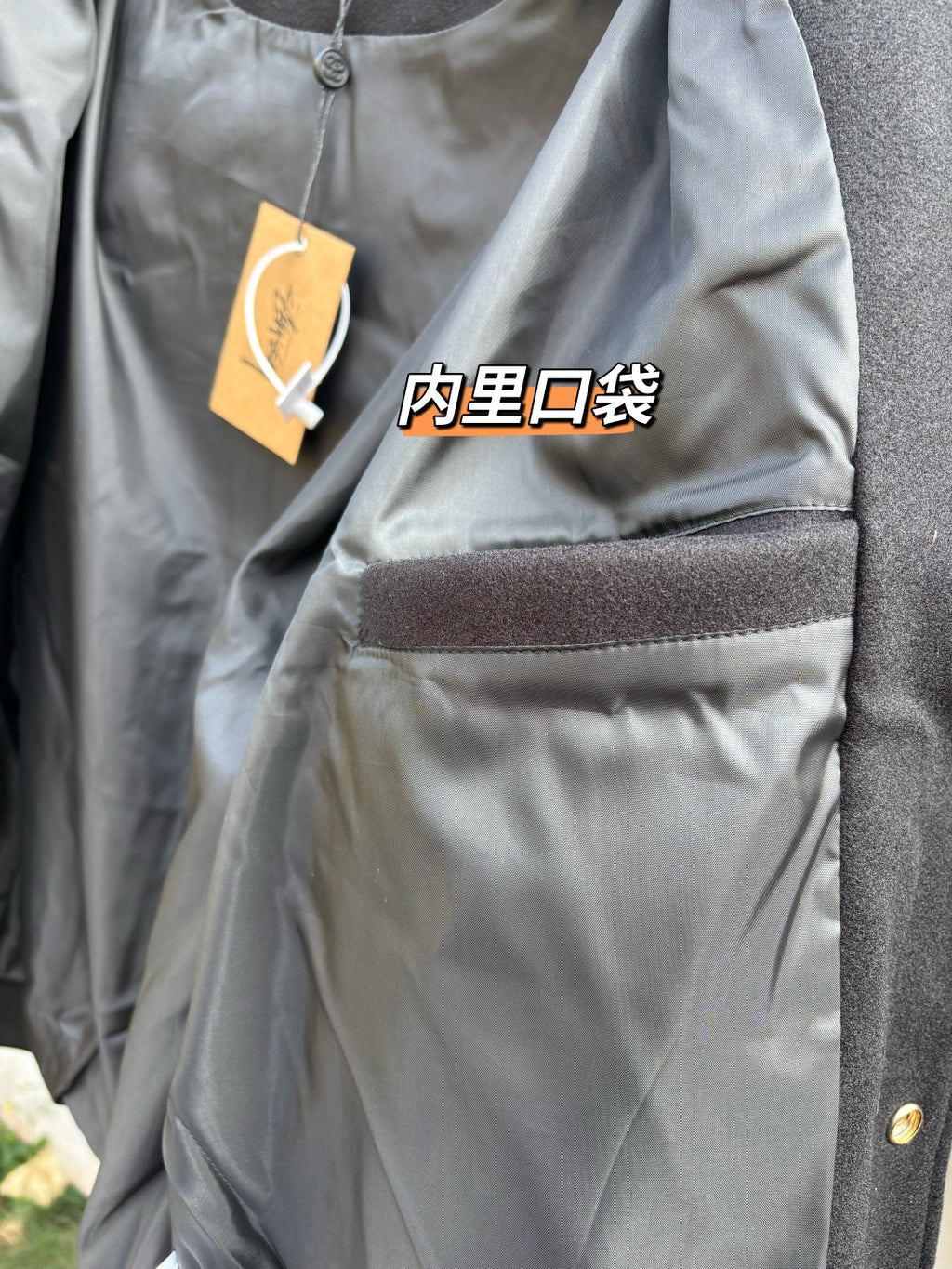 Black bomber jacket chest pocket with stitched hem and hanging tag