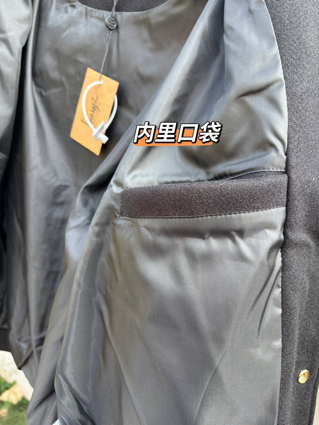 Black bomber jacket chest pocket with stitched hem and hanging tag