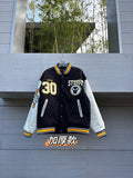 Varsity jacket with black body and white sleeves, striped collar and snap front