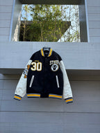 Black varsity jacket with white sleeves, yellow trim, STUSSY patch and 30 emblem