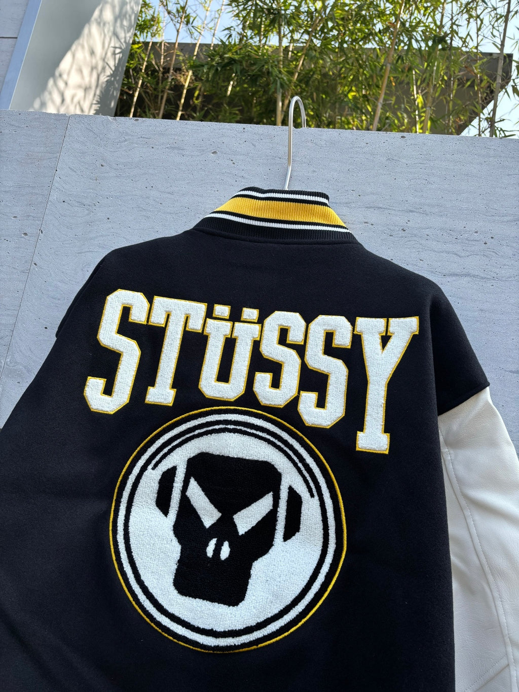 Black Stussy jacket with large back text and circular graphic emblem