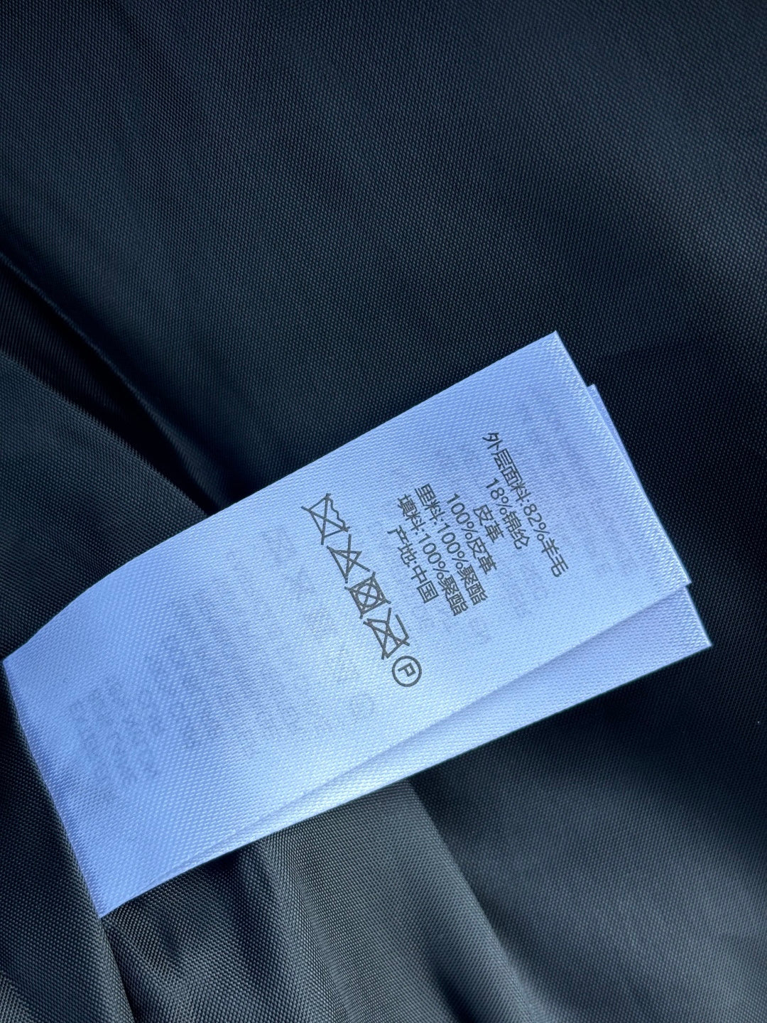 Black fabric with white care label strip showing washing symbols and text