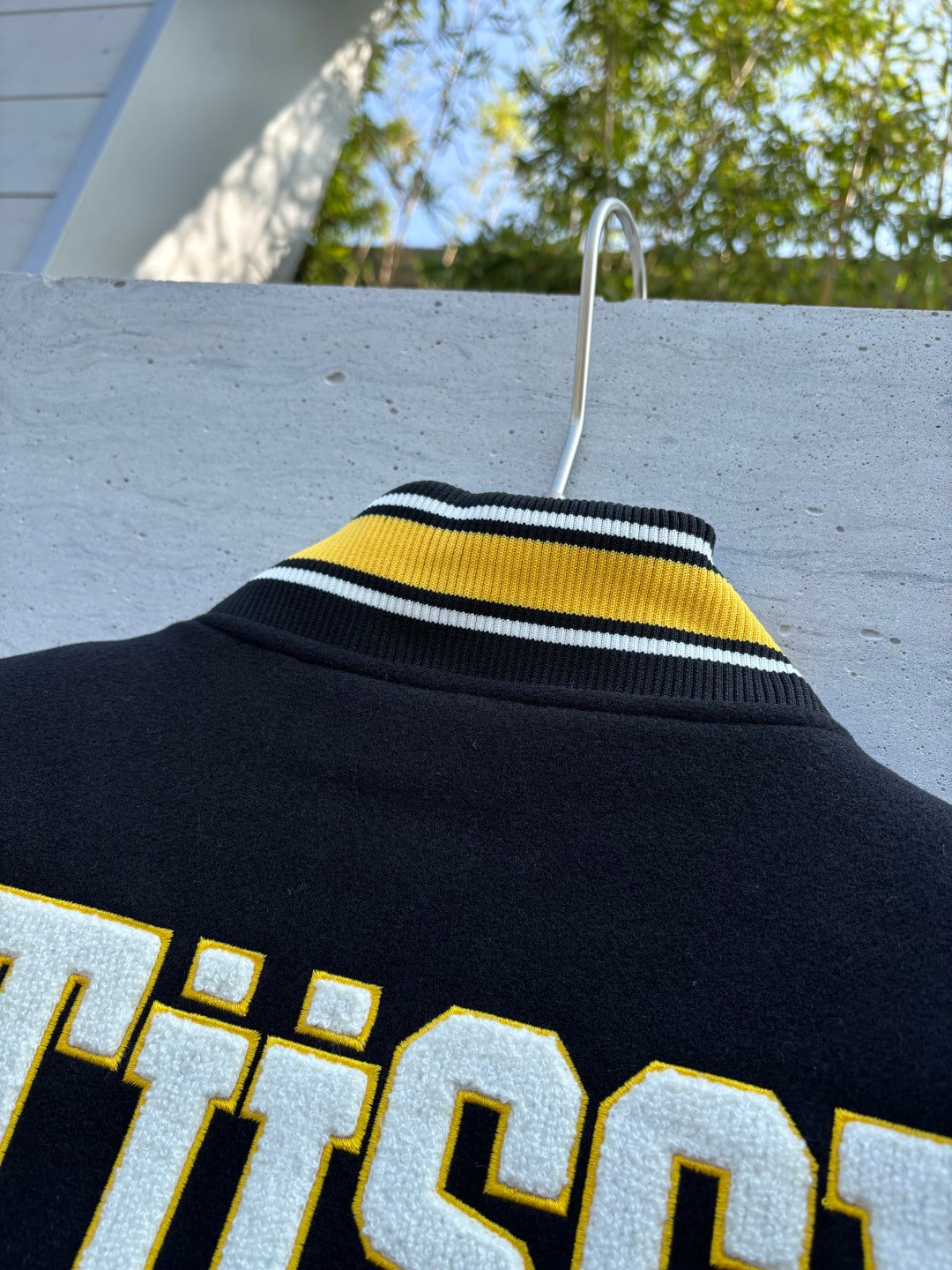 Black jacket collar with yellow and white striped rib trim and partial Stussy print