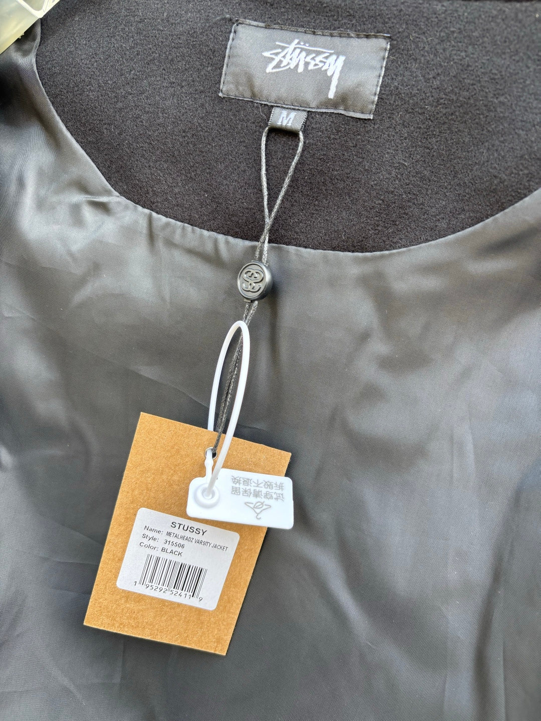 Black bomber jacket close-up of collar with size label and hanging hangtag