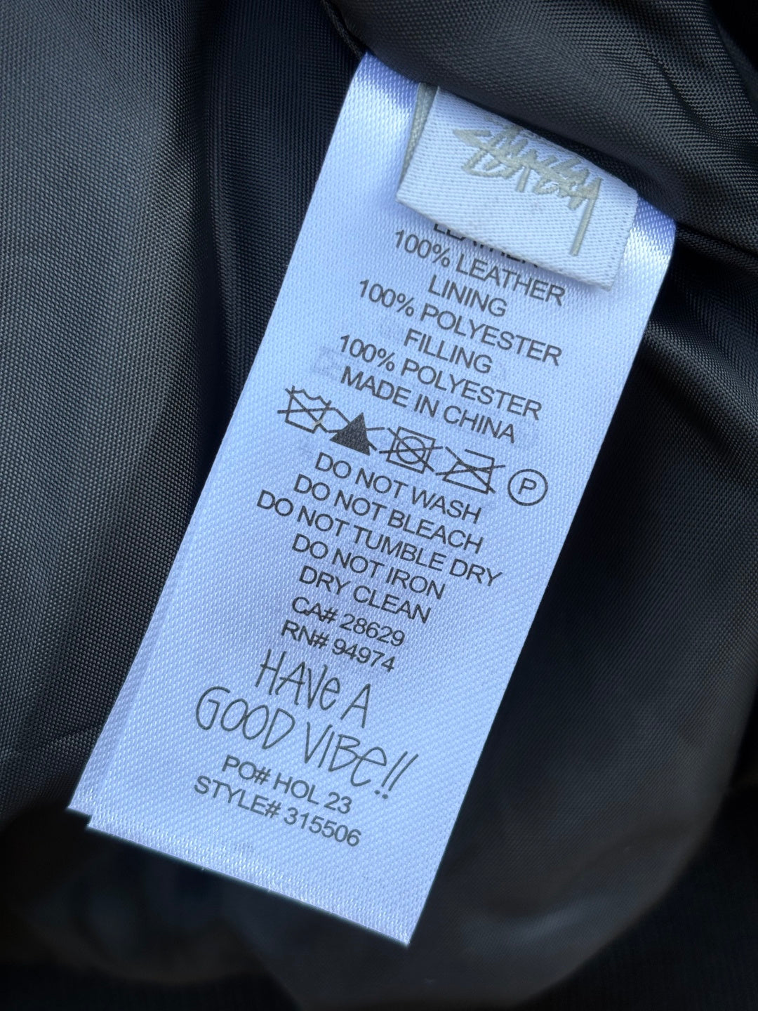 Stussy garment care label with leather and polyester materials and washing instructions