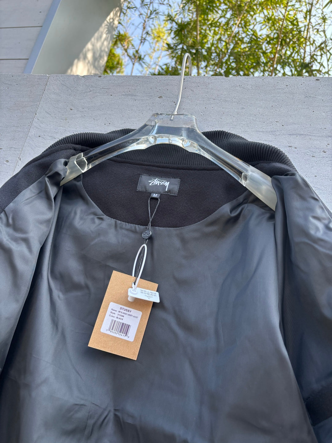 Black bomber jacket on hanger with neck label and hanging product tag