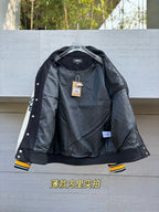Black varsity jacket interior lining shown, snap buttons and yellow striped cuffs