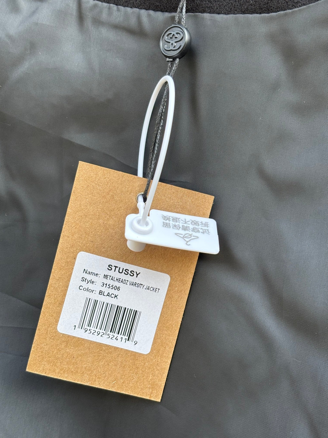 Black bomber jacket close-up of collar area with white swing tag details