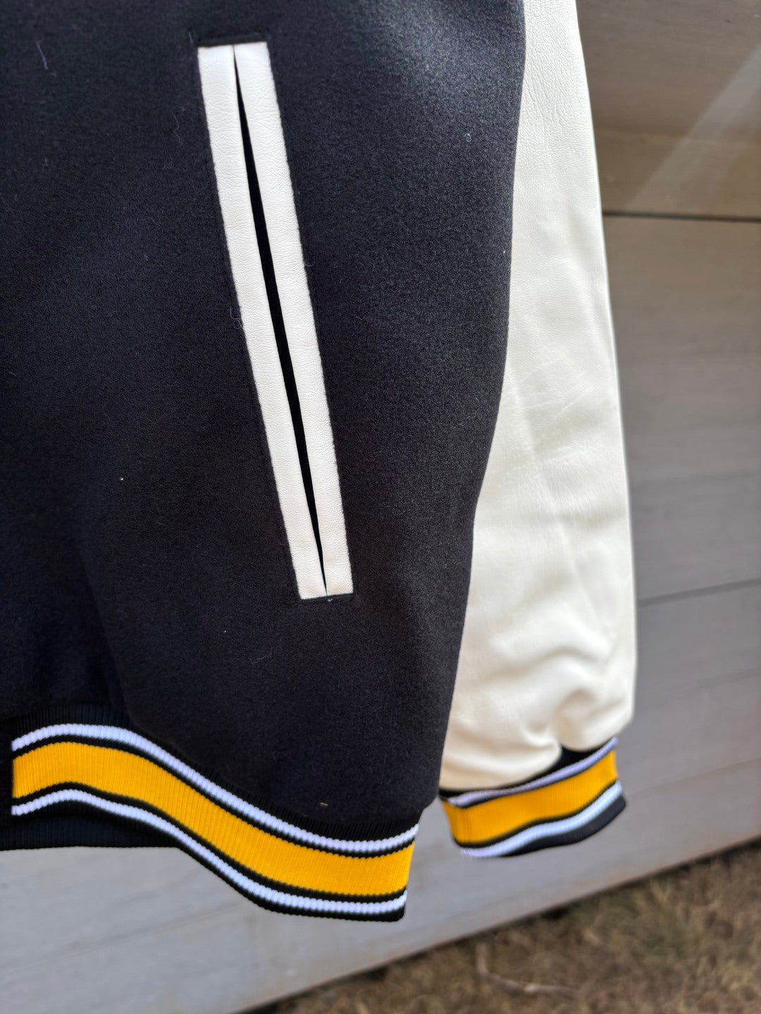 Black sleeve cuff with white stripe and yellow and blue ribbed trim