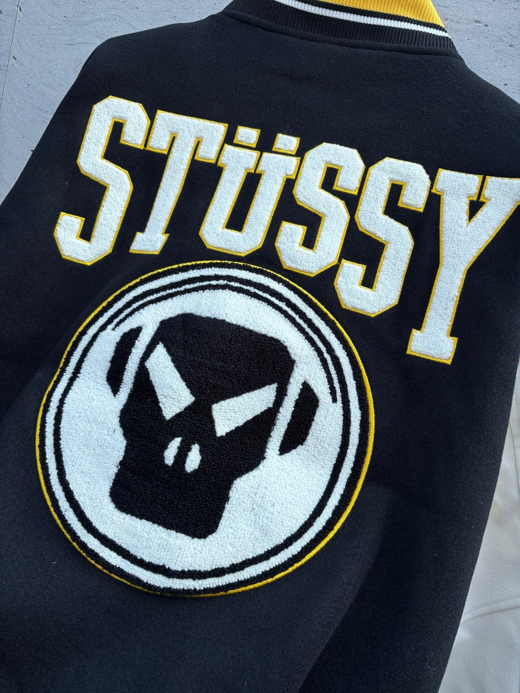 Black Stussy jacket back with raised lettering and circular logo emblem