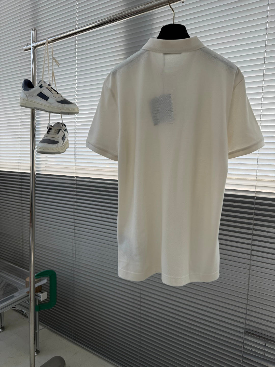 Prada short-sleeve polo shirt in off-white on hanger, front view.