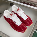 Pair of red suede Amiri sneakers with white laces and star detailing on uppers