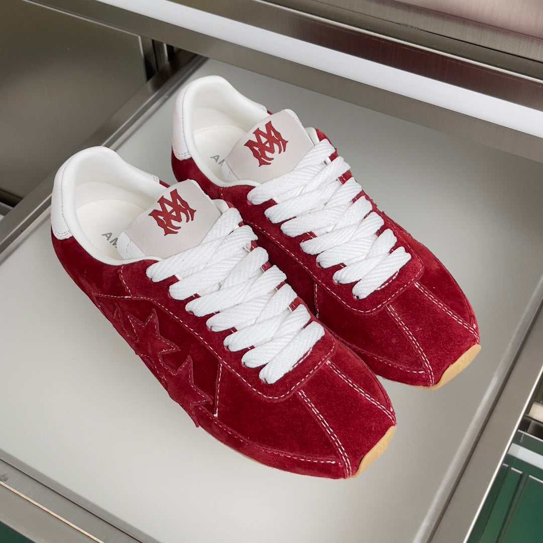 Pair of red suede Amiri sneakers with white laces and star detailing on uppers