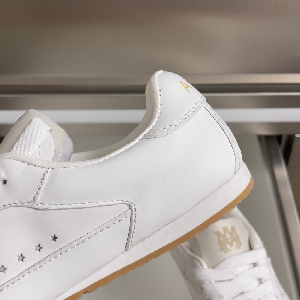 Amiri white sneaker side view with star panel, lace-up vamp, and gum sole