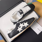 Black leather sneakers in a box with white star appliques and white lace-up front